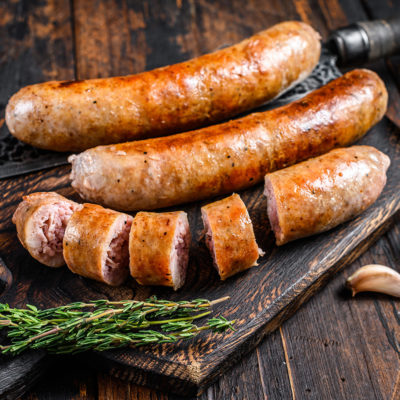 Fried and sliced pork Sausage with herbs. Top view. Dark wooden background.