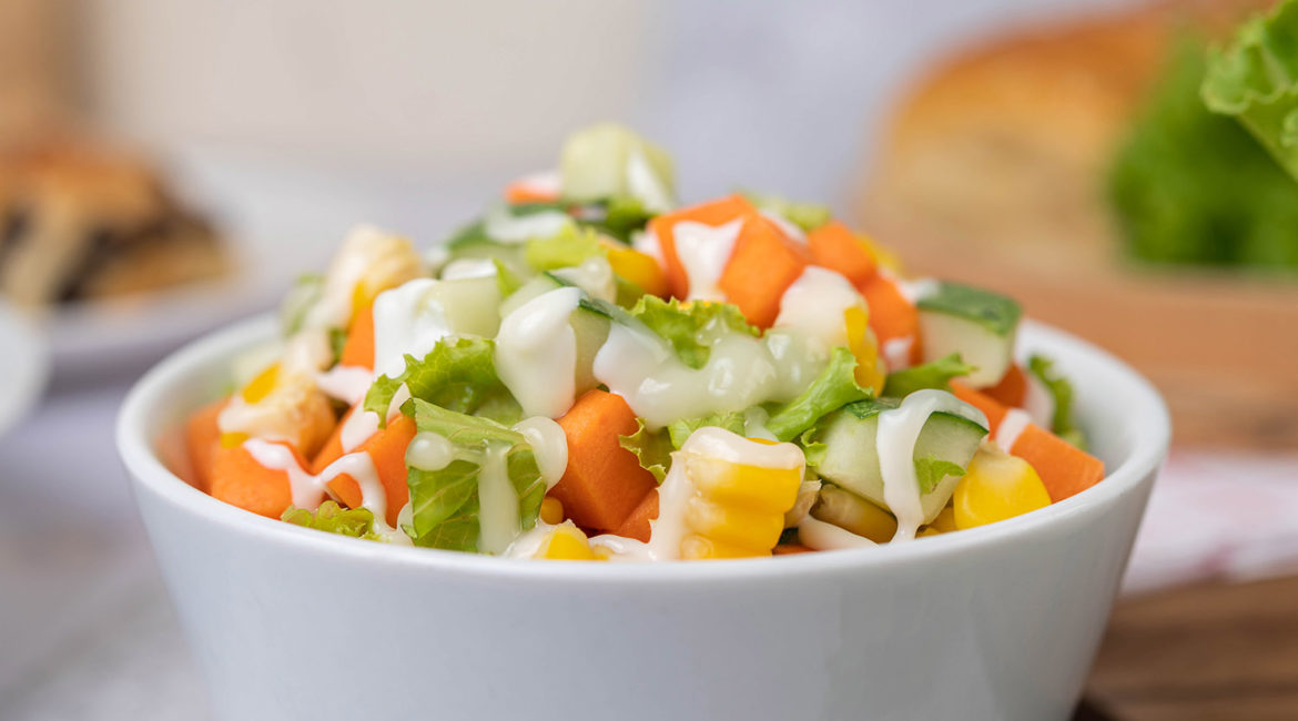 Cucumber salad, corn, carrot and lettuce in a white cup. Selective focus.